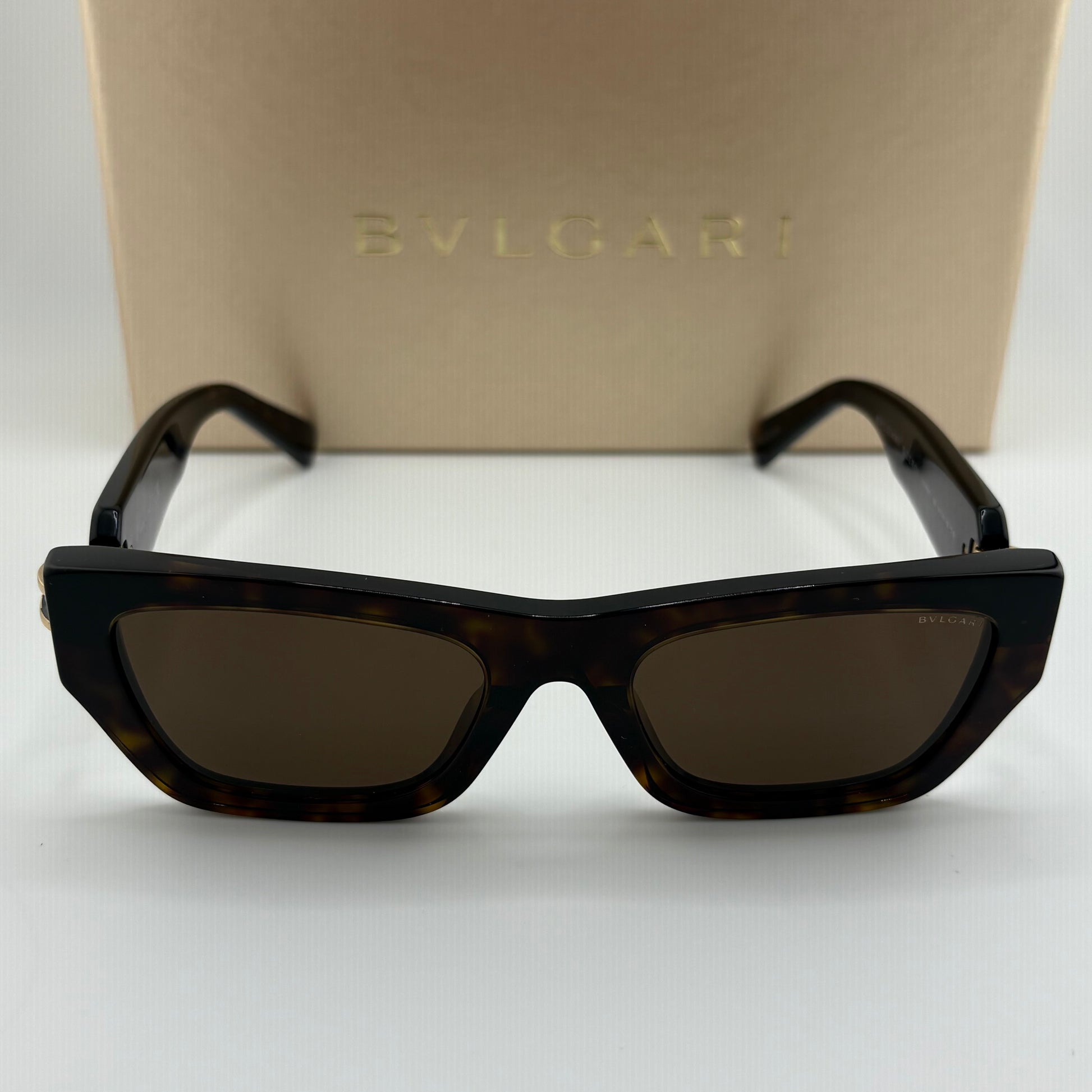 Bvlgari square sunglasses with a dark tortoiseshell frame and dark brown lenses, displayed in front of their beige Bvlgari brand box.